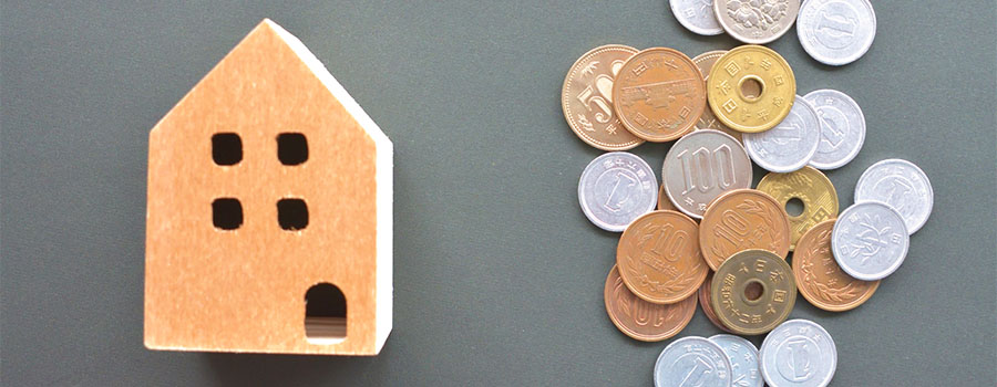 家の模型と散らばった硬貨